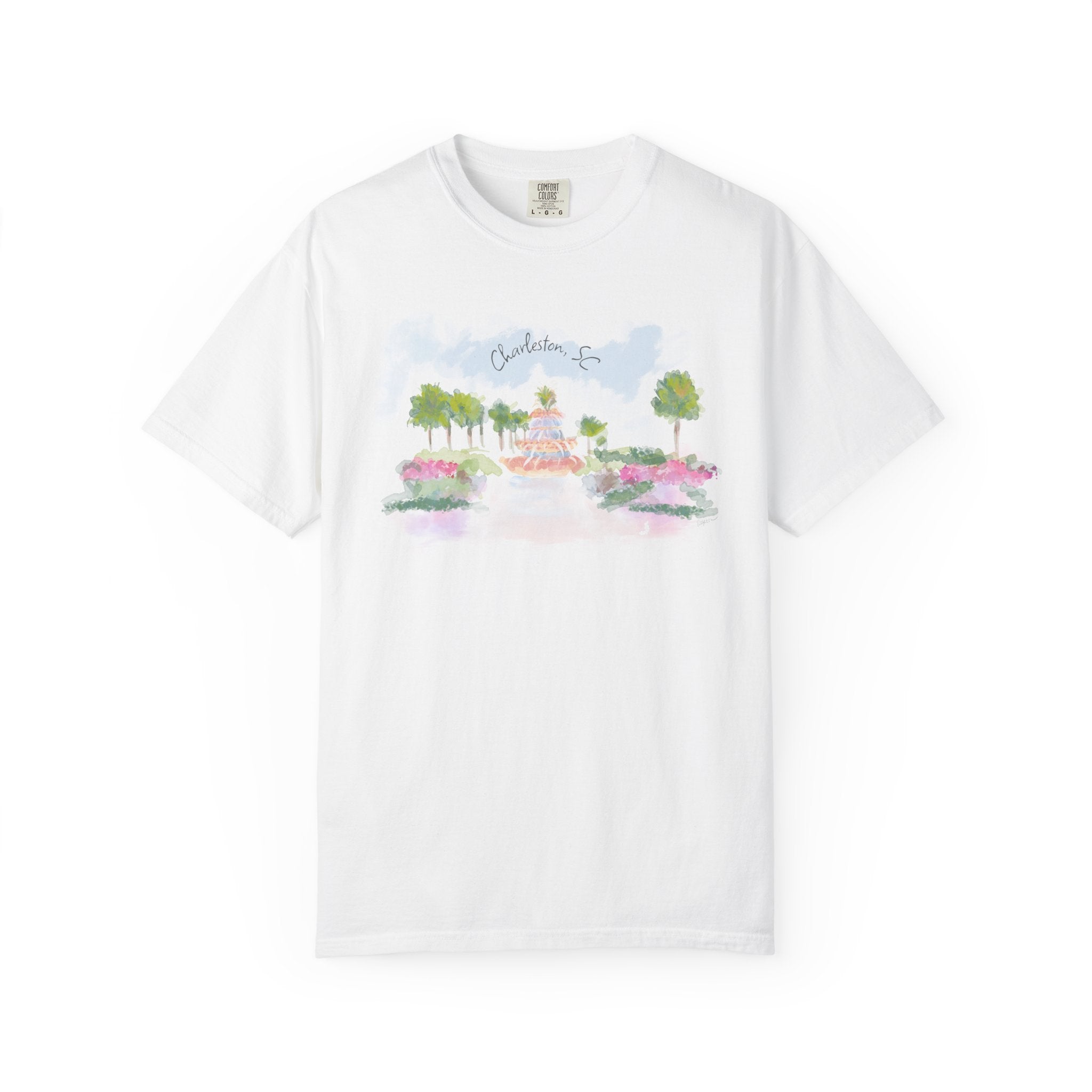 White t-shirt featuring a hand-painted illustration of the Pineapple Fountain in Charleston, SC surrounded by palm trees and colorful flowers, created by Rebecca Illustrated.