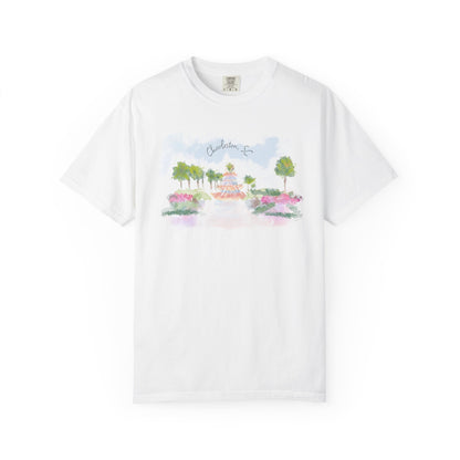 White t-shirt featuring a hand-painted illustration of the Pineapple Fountain in Charleston, SC surrounded by palm trees and colorful flowers, created by Rebecca Illustrated.