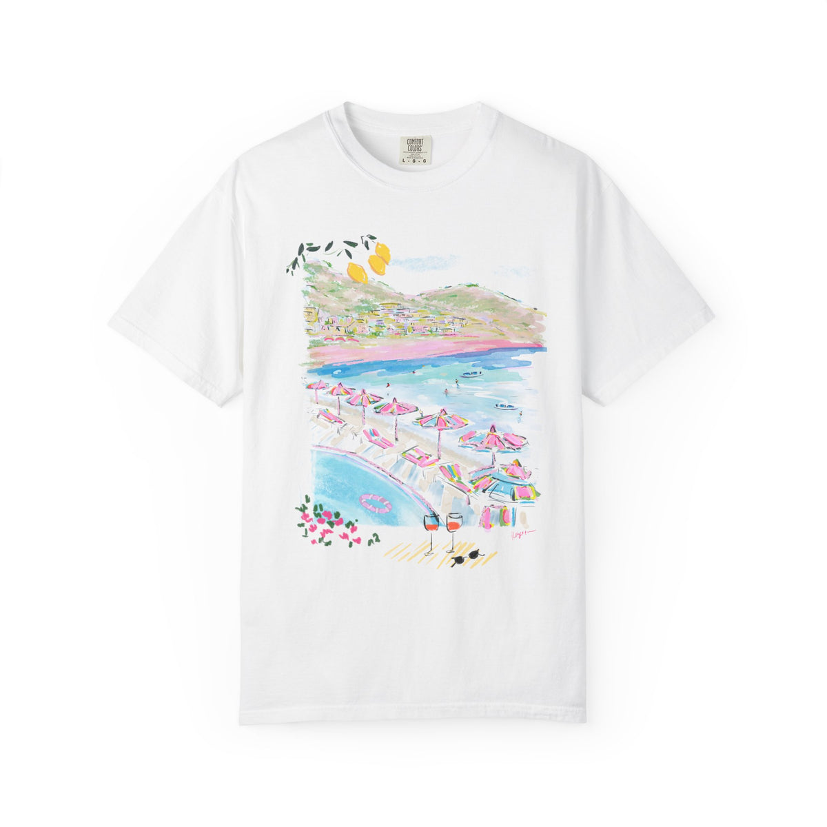 White t-shirt featuring a colorful hand-drawn Amalfi Coast beach club scene with striped umbrellas, blue Mediterranean water, and hillside villages, illustrated by Rebecca Illustrated.
