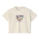Cream cropped t-shirt featuring a hand-painted brunch scene with oysters, champagne, flowers, and a Parisian-style window view, with the text ‘Morning Indulge,’ illustrated by Rebecca Illustrated."