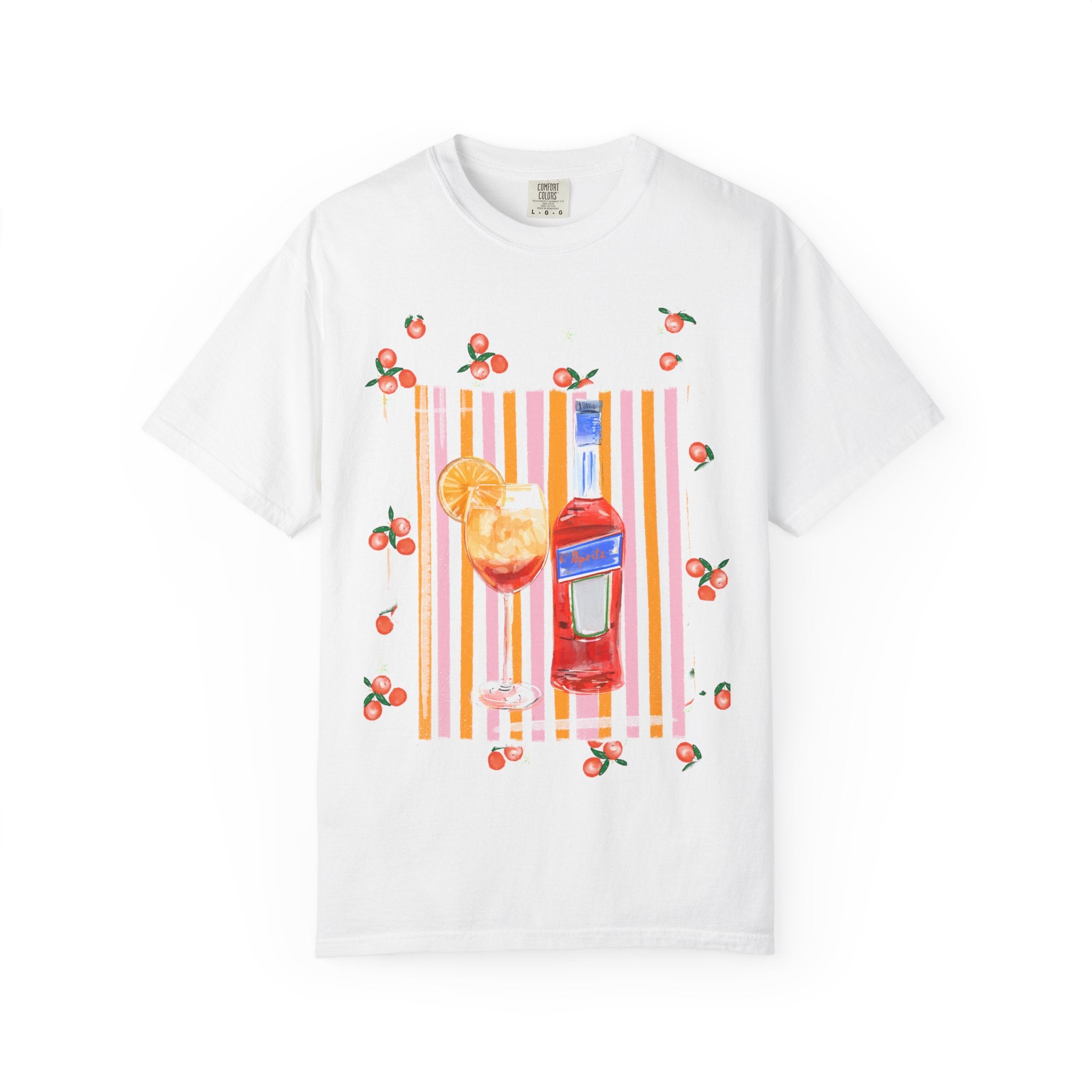 White t-shirt with a hand-painted Aperol spritz cocktail illustration, orange slice garnish, striped background, and scattered citrus details, designed by Rebecca Illustrated.