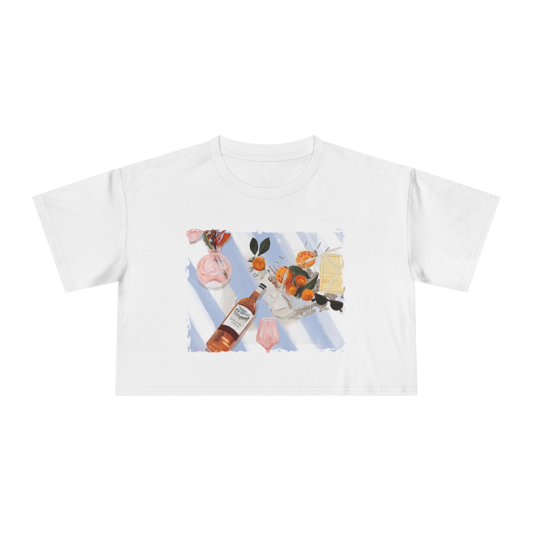 White cropped t-shirt featuring a hand-painted picnic still life with rosé wine, citrus fruits, sunglasses, flowers, and pastel blue stripes by Rebecca Illustrated."