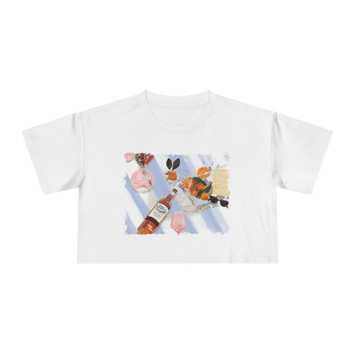 White cropped t-shirt featuring a hand-painted picnic still life with rosé wine, citrus fruits, sunglasses, flowers, and pastel blue stripes by Rebecca Illustrated."