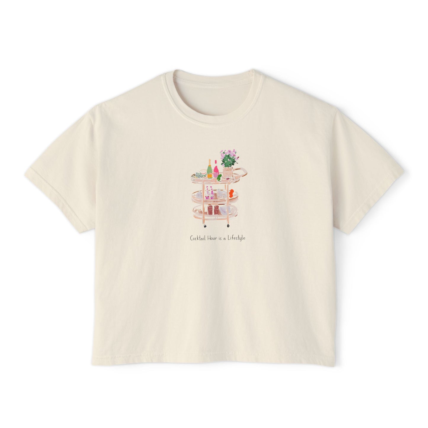 Cream cropped t-shirt featuring a hand-painted bar cart with cocktails, flowers, glassware, and the text ‘Cocktail Hour is a Lifestyle,’ illustrated by Rebecca Illustrated.