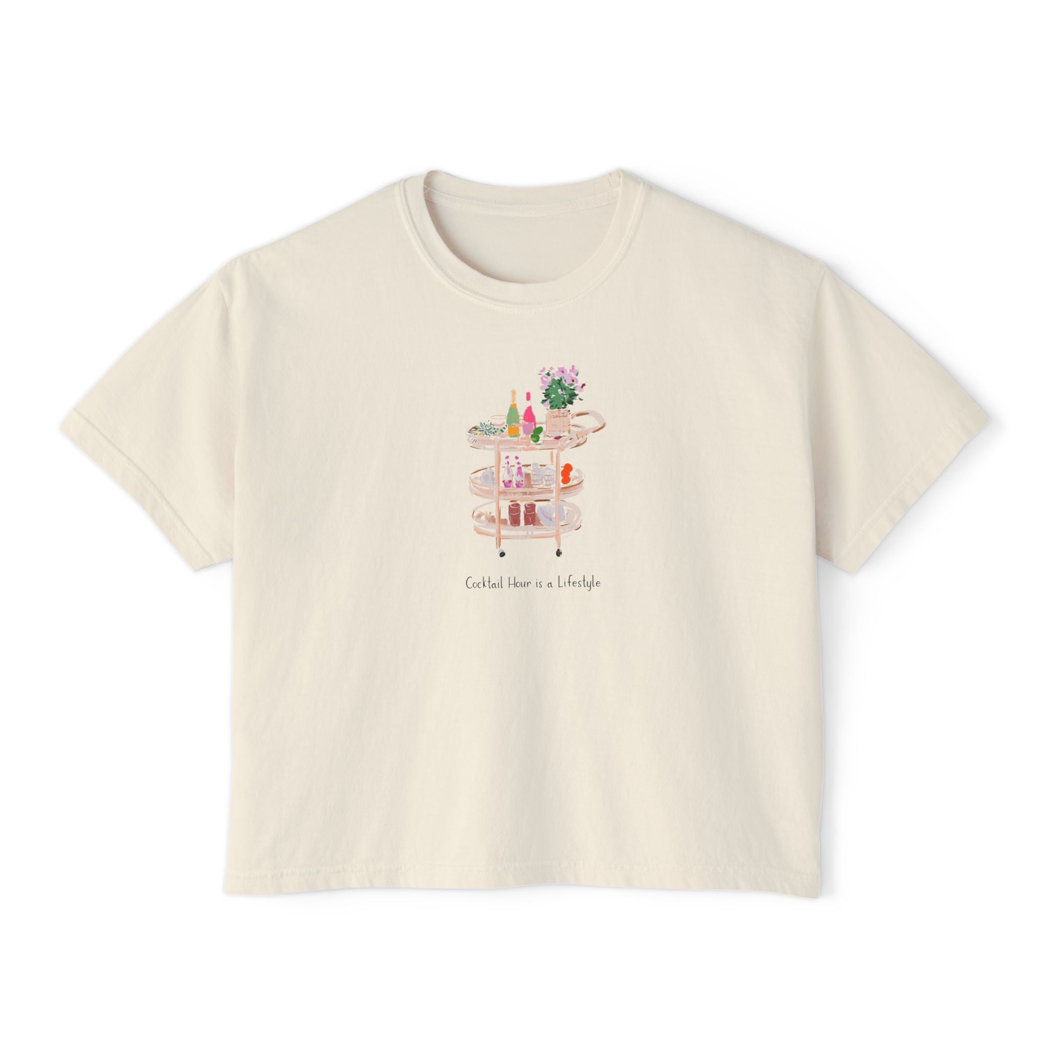 Cream cropped t-shirt featuring a hand-painted bar cart with cocktails, flowers, glassware, and the text ‘Cocktail Hour is a Lifestyle,’ illustrated by Rebecca Illustrated.