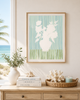 Framed artwork of a vase with flowers on a wall above a wooden console table with decor items.
