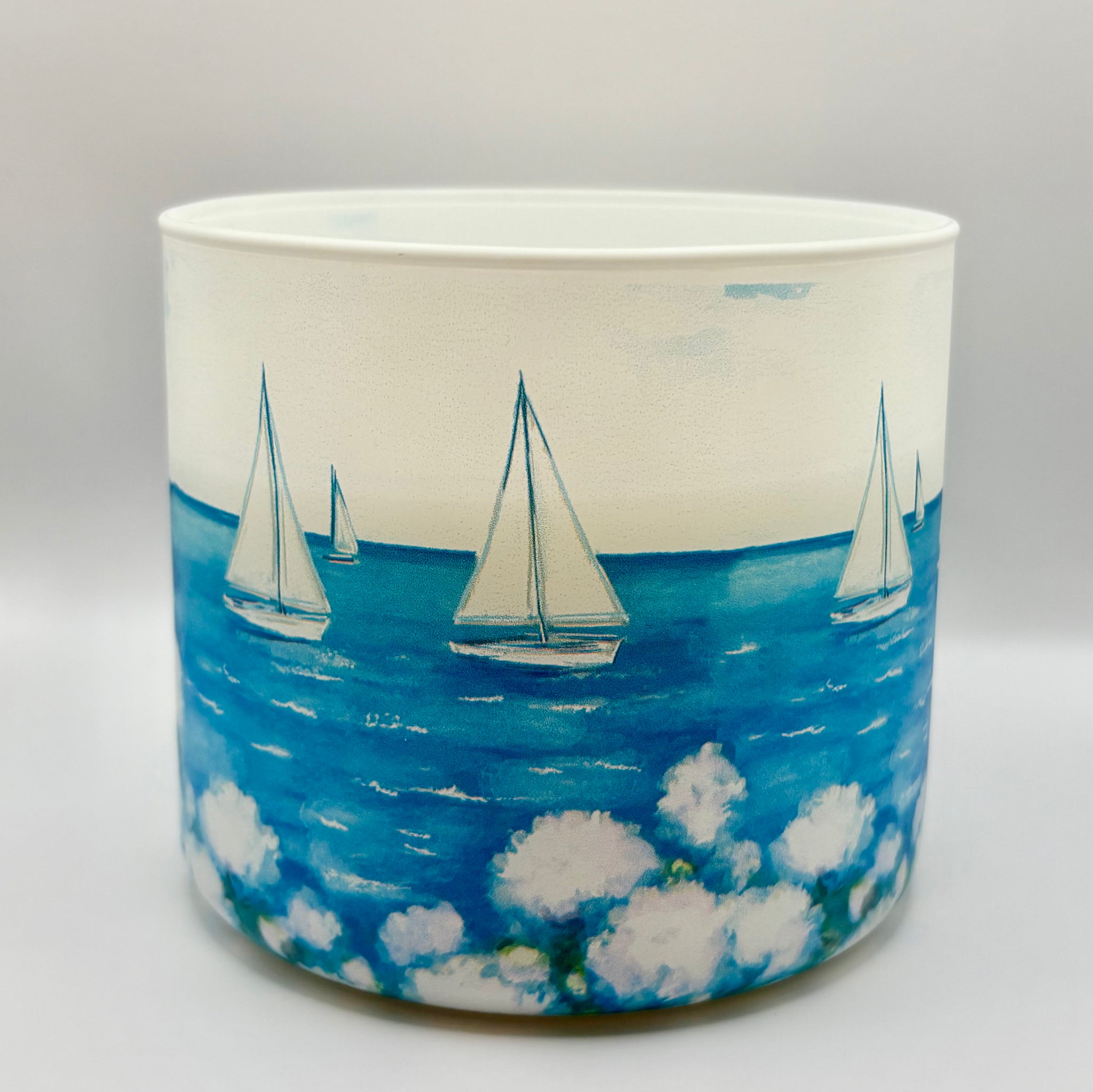 Luxury double-wick candle in a glass vessel featuring a watercolor sailboat ocean scene, original artwork by Rebecca Illustrated.