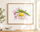 Framed artwork of a lemon in a glass bowl with pink tulips on a wall.