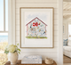 Framed artwork of a fish house with a red roof in a living room setting.