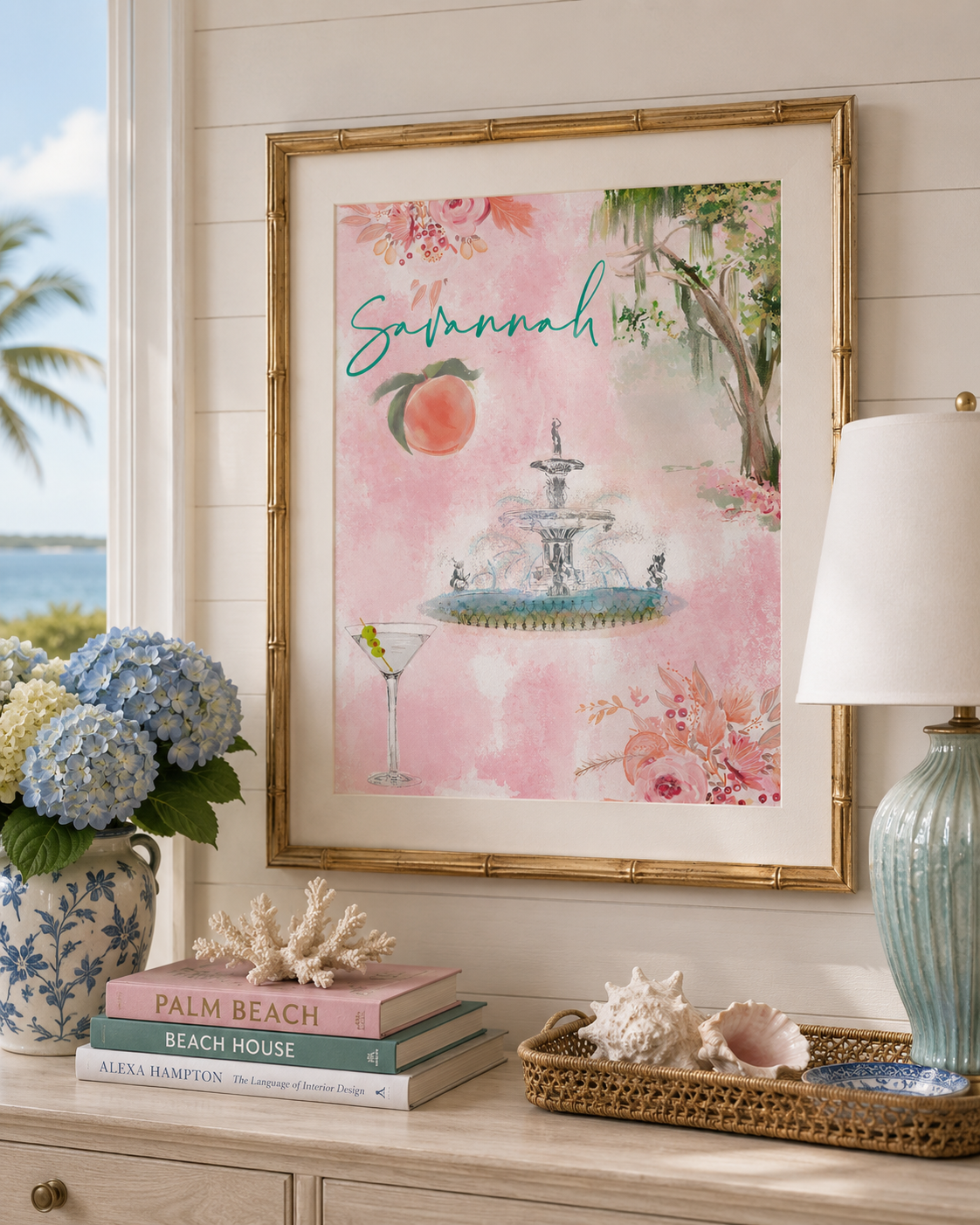 Decorative setting with a framed artwork of a fountain and peach, books, and a lamp.
