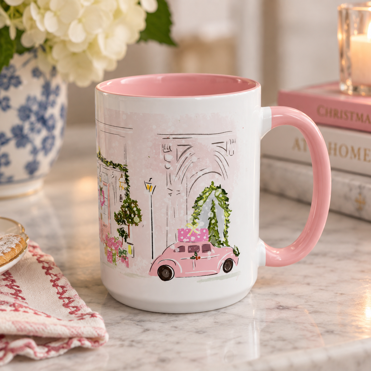 A white ceramic mug with a pink interior and handle, decorated with a delicate illustration of a pink car, green ivy, and architectural details, set on a marble countertop with a blurred background.