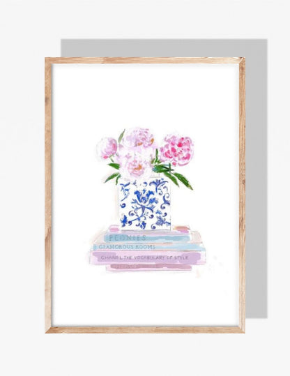 A soft pastel illustration by Rebecca Illustrated of pink peonies in a blue-and-white chinoiserie vase placed on a stack of fashion and design books.