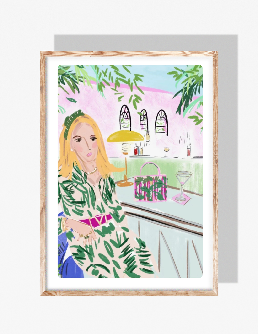 Illustration of a stylish blonde woman in a green palm-print dress sitting at an outdoor bar with martini, handbag, and greenery, artwork by Rebecca Illustrated.
