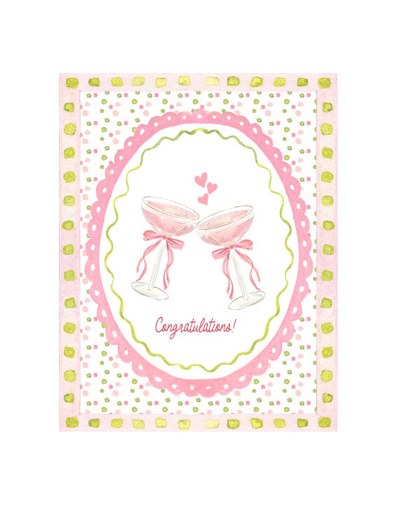 Illustrated congratulations greeting card featuring two pink cocktail glasses with bows, hearts, and a decorative pink patterned border, by Rebecca Illustrated.